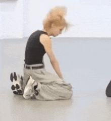 a woman is kneeling on the floor wearing a black tank top