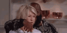 a man and a woman are hugging each other in a room . the woman is wearing a striped shirt .