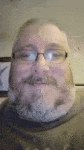 a man with glasses and a beard is smiling at the camera