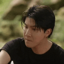 a close up of a man 's face wearing a black shirt and earrings .