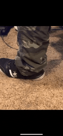 a person wearing camo pants and black sneakers