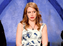 a woman in a blue and white dress is sitting in front of a blue background