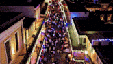 an aerial view of a crowd of people walking down a street with christmas lights