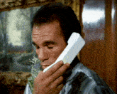 a man is talking on a cell phone with a painting in the background