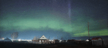 the aurora borealis is visible in the night sky over a small village