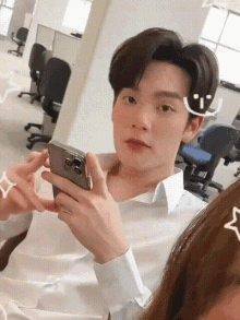 a man in a white shirt is holding a phone in his hand