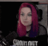 a woman with purple hair is wearing headphones and a black shirt .