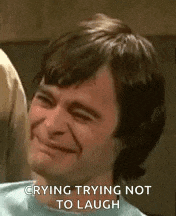 a man is crying and trying not to laugh while making a funny face .