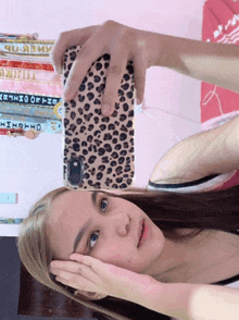 a woman taking a selfie with a leopard print cell phone