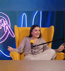 a woman sitting in a yellow chair with a microphone