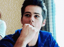 a young man with his hand on his chin is looking at the camera