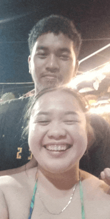 a man and a woman are posing for a picture and the man is wearing a black shirt with the letter j on it