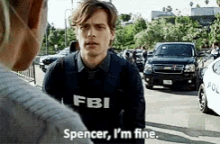 a man in a fbi sweater is talking to a woman in a parking lot .