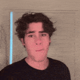 a young man making a funny face in front of a white wall