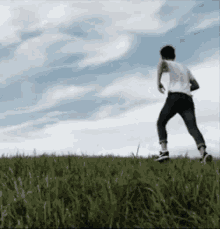 a man in a white shirt and jeans is running in a grassy field