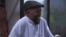 a man wearing a hat and a blue shirt laughs
