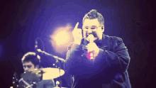 a man singing into a microphone with his middle finger up