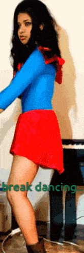 a woman in a blue top and red skirt is dancing in front of a piano with the words break dancing below her