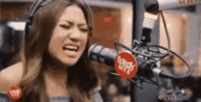 a woman wearing headphones is singing into a microphone in a radio station .
