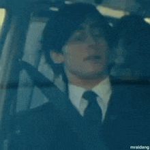 a man in a suit and tie is sitting in a car with another man .