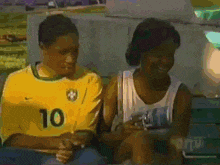a man wearing a yellow shirt with the number 10 on it sits next to a woman