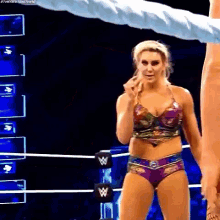 a woman in a bikini is standing in a wrestling ring with a man .