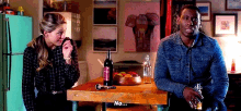 a man and a woman are sitting at a table with a bottle of wine on it and the word no on the table