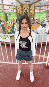 a girl standing in front of a merry go round at an amusement park