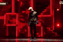 a man is standing on a stage in front of a red wall .