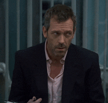 a man in a suit and a pink shirt looks serious
