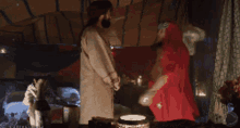 a woman in a red cape is standing next to a man