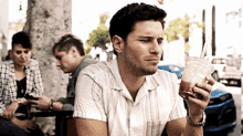 a man is sitting at a table holding a drink in his hand .