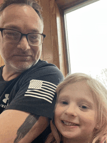 a man wearing an under armour shirt holds a young girl
