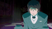 a man in a suit and bow tie is sitting on the floor in a dark room .