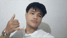a young man in a white shirt is giving a thumbs up sign