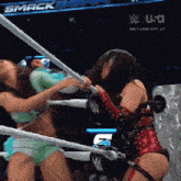 two women are wrestling in a ring with a sign that says smack down on it