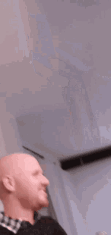 a bald man is holding his hand to his chin and looking at the camera .