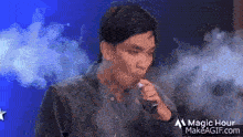 a man is blowing smoke into a microphone while smoking an electronic cigarette .
