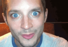 a close up of a man 's face with blue eyes making a funny face