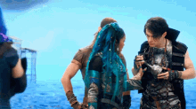 a woman with blue hair is standing next to a man