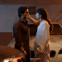 a man and a woman are kissing in front of a car ..