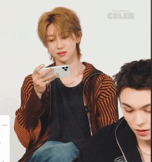 a man looking at a cell phone with buzzfeed celeb on the bottom right