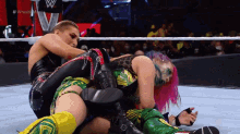a woman with pink hair is wrestling another woman in a ring