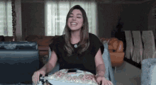 a woman is sitting on a couch in a living room laughing while holding a plate .