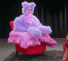 a woman in a purple bear costume is sitting in a red chair
