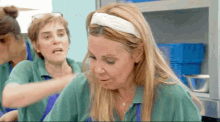 a woman wearing a white headband is making a funny face while another woman holds her hair .