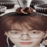 a close up of a person wearing glasses with a chocolate cupcake on their head .