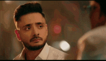 a man with a beard is looking at another man 's face .