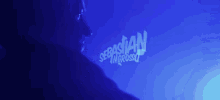 a man stands in front of a blue background that says sebastian ingrosso