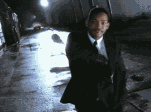 a man in a suit and tie is walking down a wet sidewalk